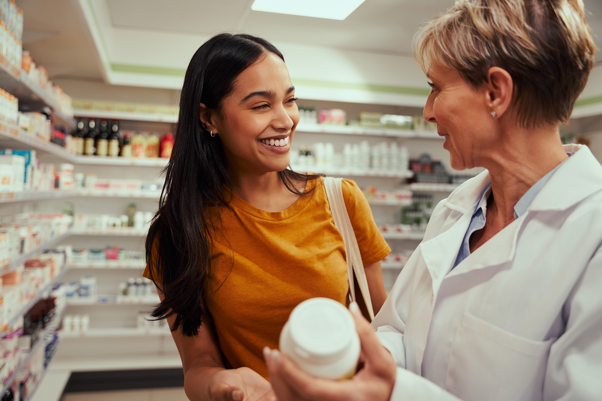 Senior pharmacist assisting in buying medical drug to buyer in pharmacy